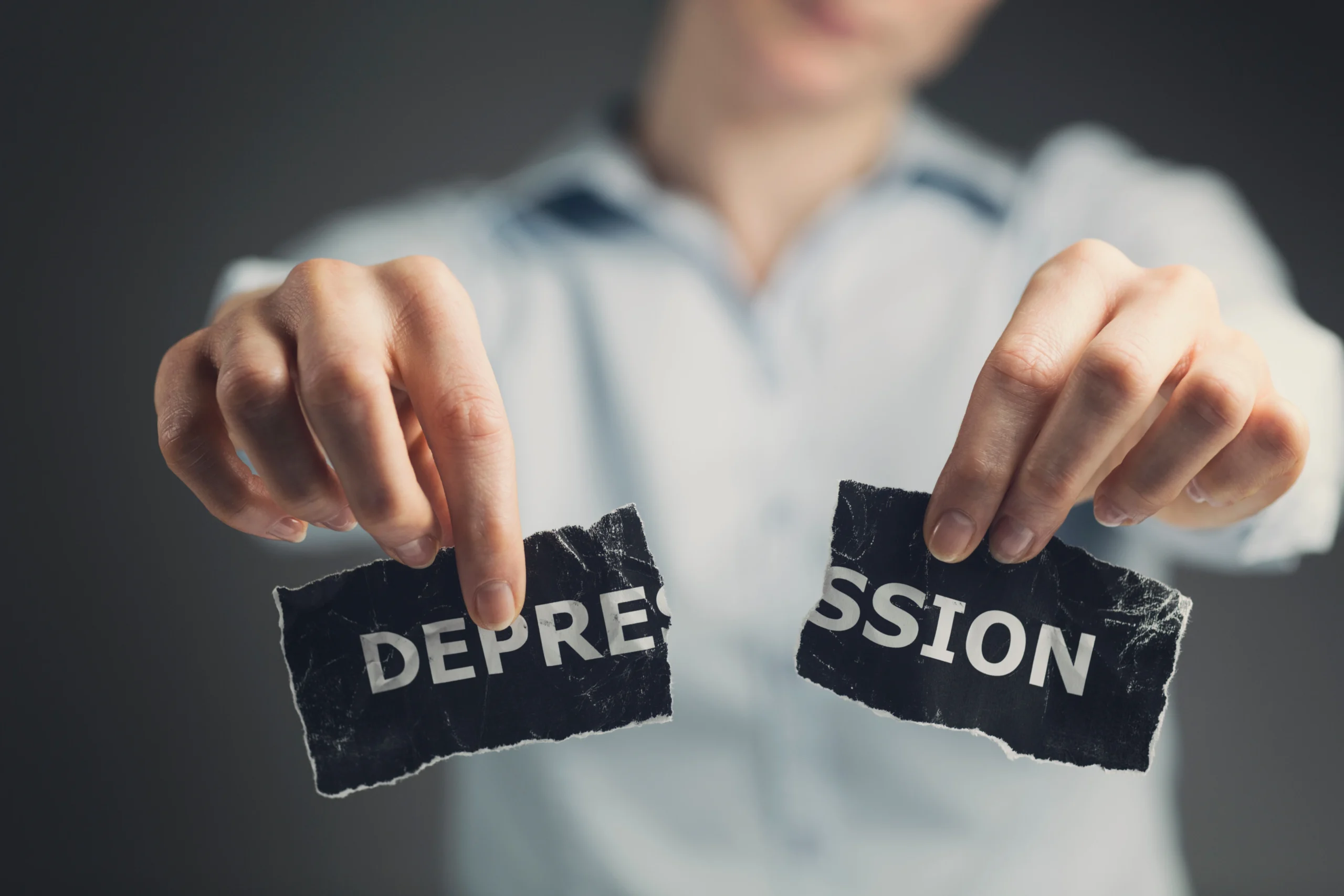 Person tearing a paper with the word depression on it, representing hope and recovery from treatment-resistant depression through advanced treatment options at Georgia Behavioral Health in Atlanta
